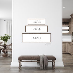 May include: Three brown picture frames with white mats are hung on a white wall. The frames are nested, with the smallest frame at the top and the largest frame at the bottom. The frames are labeled with the dimensions 10x30, 12x36, and 16x47. The word "NESTED" is written below the frames.