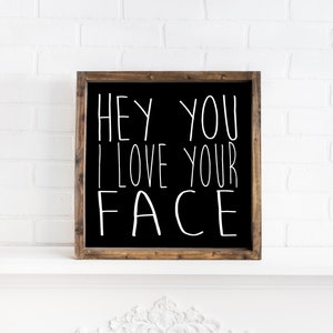 K&ouml;nnte beinhalten: Schwarzes, gerahmtes Schild mit wei&szlig;em Text, der "Hey you I love your face" lautet.