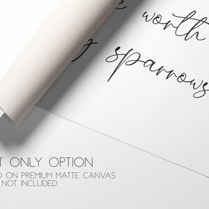 May include: A white matte canvas print featuring black cursive text that reads, "worth sparrows." The canvas is partially rolled at the top left corner. Below the text, the words "PRINT ONLY OPTION" and "PRINTED ON PREMIUM MATTE CANVAS FRAME NOT INCLUDED" are visible.