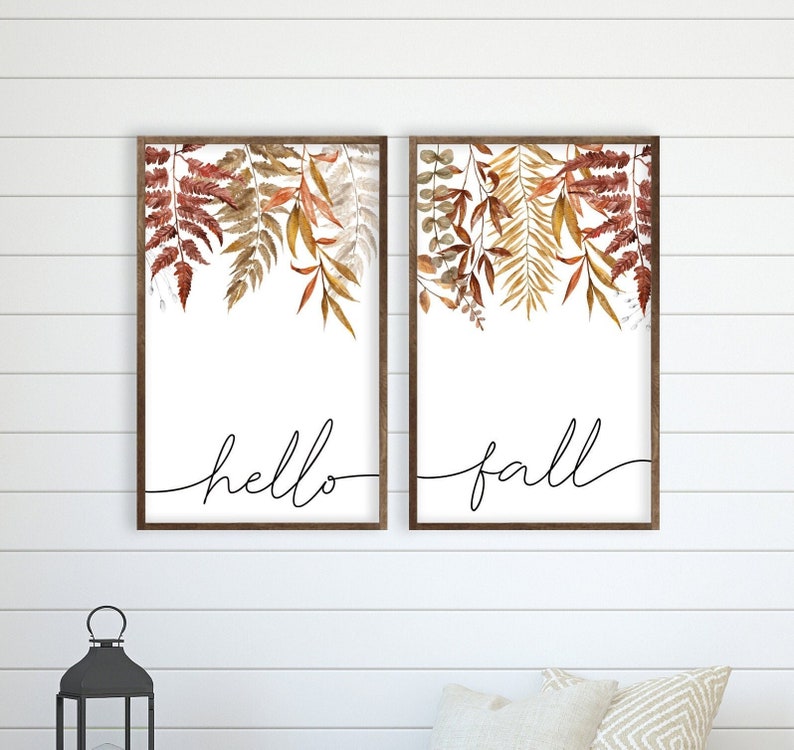 May include: Two framed prints with watercolor illustrations of autumn leaves. The prints have white backgrounds and black calligraphy that reads "hello fall".