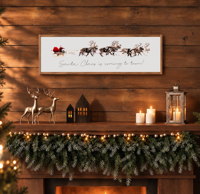 Puede incluir: Un letrero de pared rectangular con marco de madera y fondo blanco, que presenta un gr&aacute;fico de Santa Claus en un trineo tirado por renos y el texto cursivo negro Santa Claus is coming to town! centrado bajo la ilustraci&oacute;n.