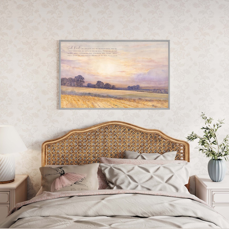 A framed print with a watercolor painting of a field with trees and a sunset sky. The print has a quote from the Bible: "Seek first his kingdom and his righteousness, and all these things will be given to you as well." Matthew 6:33.
