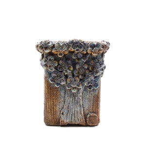 May include: A ceramic planter with a blue and brown glaze. The planter is decorated with a raised design of flowers around the top.