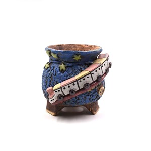May include: A whimsical, blue ceramic planter with a textured surface and a decorative train circling the pot. The planter features yellow star accents and a brown rim. The train is painted in pastel colors, adding a playful touch to this unique piece.