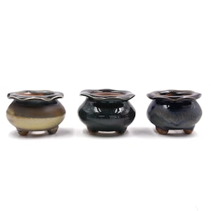 May include: Three small ceramic pots with scalloped rims. The pots are glazed in different shades of green and brown.