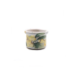 May include: A small, off-white ceramic pot with a rounded rim. The pot is decorated with a yellow floral pattern and green leaves. The pot is likely used for decorative purposes.
