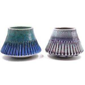 Könnte beinhalten: Zwei Keramikschalen mit geriffeltem Design und einem gesprenkelten Überzug. Eine Schale ist blau und grün, die andere ist lila und weiß.