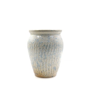 Peut inclure: Un vase en céramique blanche avec un glaçage moucheté bleu et blanc. Le vase a un design texturé et côtelé.