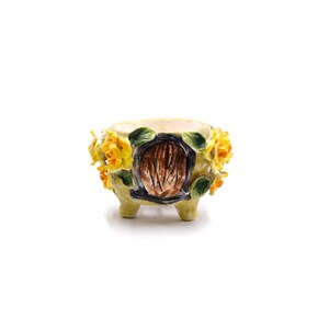 以下が含まれることがあります： 茶色のドアのデザインと黄色の花のアクセントが付いた黄色のセラミックプランター