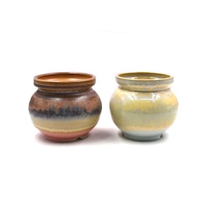 May include: Two ceramic pots, one with a brown, yellow, and pink glaze and the other with a yellow and blue glaze.