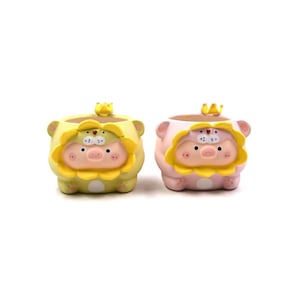 May include: Two small, round planters shaped like pigs wearing yellow lion manes and tiny crowns. One planter is light green, and the other is light pink. Both feature a pig face with a snout, small ears, and a wide, open top for planting.