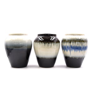 May include: Three ceramic vases with a white, black and blue glaze. The vases are round and have a wide mouth.
