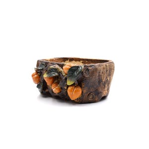 May include: A brown ceramic planter shaped like a tree trunk with orange and green persimmon fruit details.