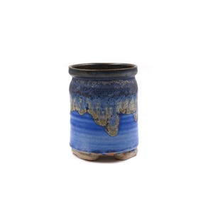 Peut inclure: Une tasse en céramique cylindrique avec un bord brun foncé qui se transforme en un vernis bleu marine profond. La section centrale présente un ton bleu plus clair avec un effet de vernis coulant texturé dans des tons beige et or.