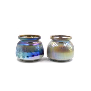 May include: Two iridescent ceramic pots with a rounded shape and a slightly flared lip. The pot on the left has a blue and green iridescent glaze, while the pot on the right has a gold and brown iridescent glaze.