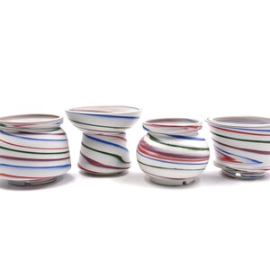May include: Four small ceramic pots with a white base and swirling red, blue, and green stripes. The pots are arranged in a row on a white surface.