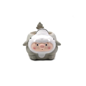 May include: A gray and white ceramic planter shaped like a pig wearing a shark costume. The pig has a pink snout, black eyes, and rosy cheeks, while the shark suit features a dorsal fin on top, side fins, and a hood framing the pig's face.
