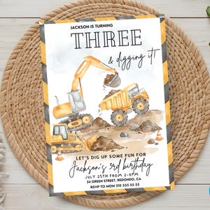 Construction birthday invitation displayed on woven mat featuring dump truck, excavator and bulldozer, editable Canva birthday invitation template, construction truck birthday party invite, digger themed birthday celebration for boys, printable construction birthday card, heavy machinery party invitation, personalized truck birthday invitation, instant download construction party decor and supplies.
