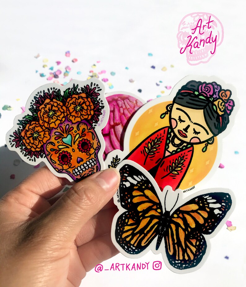 May include: Three colorful stickers featuring a sugar skull with marigolds, a butterfly, and a Frida Kahlo-inspired illustration. The stickers are on a white background with confetti.