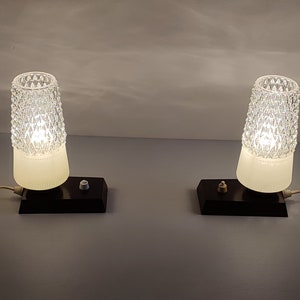 May include: Two vintage table lamps with white frosted glass shades and clear diamond-shaped patterned glass tops. The lamps have black bases with a single switch on each.