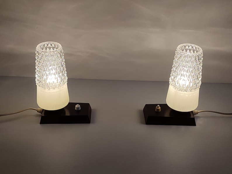 May include: Two vintage table lamps with white frosted glass shades and clear diamond-shaped patterned glass tops. The lamps have black bases with a single switch on each.