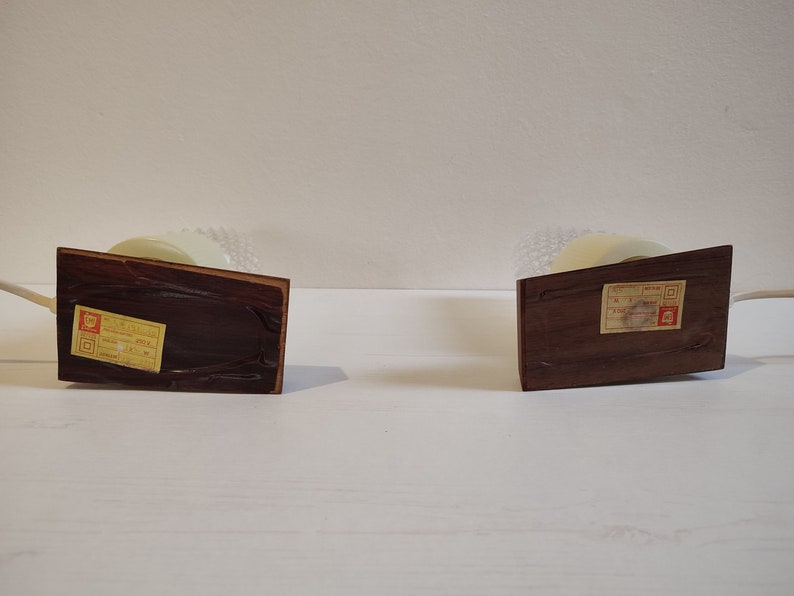 May include: Two wooden table lamps with white shades and labels on the bottom. The labels are in Japanese.