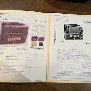 May include: A vintage Emerson Radio & Phonograph Corporation model 559AA Ch. 1200794 radio. The radio is brown with a crocodile-patterned leather case. The radio has a dial with numbers 5, 6, 7, 8, 9, 10, and 11. The radio is battery-operated.