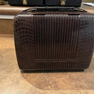 May include: A brown vintage Emerson Radio & Phonograph Corporation Model 111 radio with a crocodile-embossed leatherette case and a metal handle.
