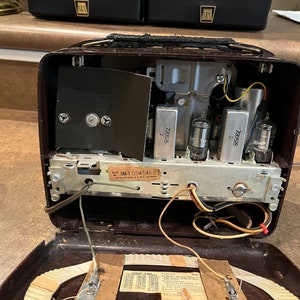 May include: A vintage brown radio with the inside exposed, showing the wiring, tubes, and a label that reads "SM-1 0945468".