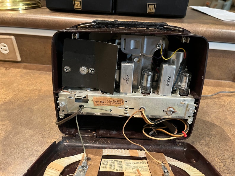 May include: A vintage brown radio with the inside exposed, showing the wiring, tubes, and a label that reads "SM-1 0945468".