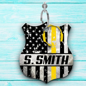 May include: A black and white American flag with a yellow stripe down the center. The flag is on a metal keychain with a silver ring. The keychain has the text "S. SMITH" on it.