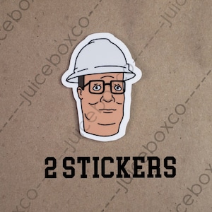 May include: Two white and black stickers featuring a cartoon illustration of a man wearing a white hard hat and glasses. The text "2 STICKERS" is printed below the image.