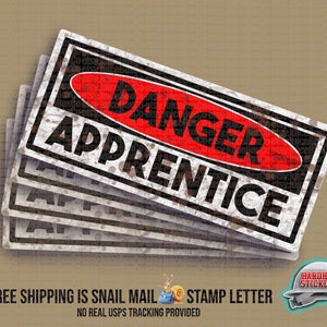 May include: A set of five black and white warning stickers with the text "DANGER APPRENTICE" in red. The stickers have a distressed, rusty look.