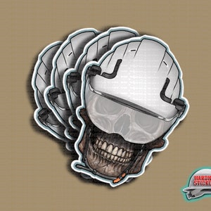 May include: A set of four white hard hat stickers with a skull design and a visor. The skull is wearing a hard hat and has a pair of goggles. The stickers are for sale on Hardhat Stickers.