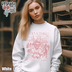 Könnte beinhalten: Weißer Pullover mit einem rosafarbenen Aufdruck einer Frau, die ein Pferd reitet, mit dem Text "I do a thing called what I want".