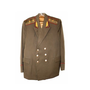 May include: A brown military jacket with gold and red trim on the collar. The jacket has a double-breasted closure with gold buttons.