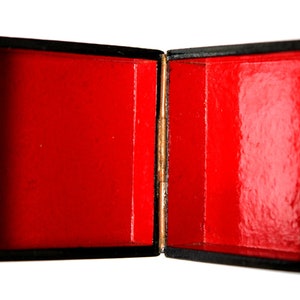 May include: A black wooden box with a red velvet interior. The box is open and the lid is propped up.