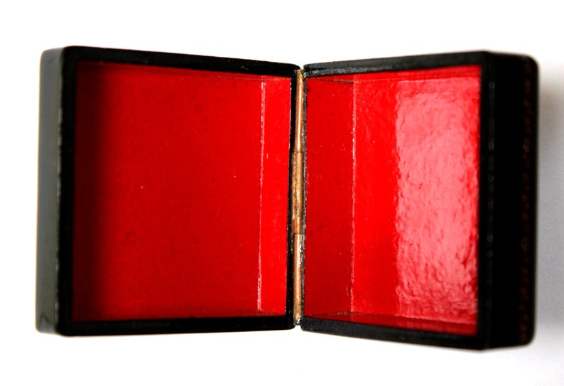 May include: A black wooden box with a red velvet interior. The box is open and the lid is propped up.
