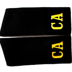 Puede incluir: Dos parches de tela negra con letras bordadas en oro que deletrean "CA".