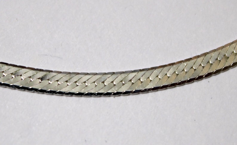 May include: A silver snake chain necklace with a shiny finish.