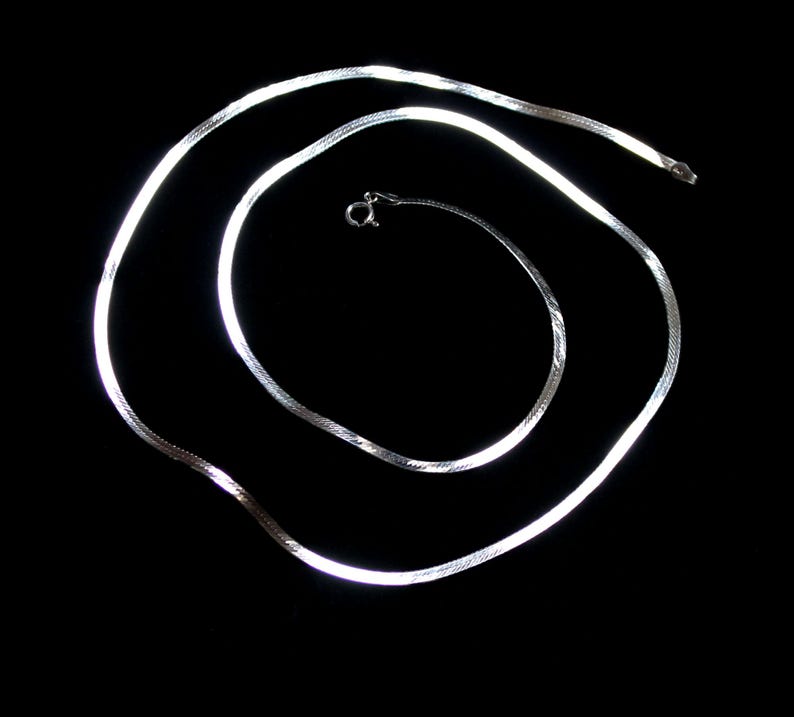 May include: A silver snake chain necklace with a clasp.