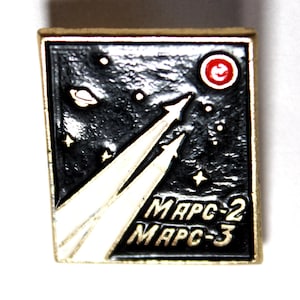 May include: A square pin with a gold border. The black background features white stars, a planet, and a red and white circle. Two white and silver streaks ascend from the bottom, with the text "MAPC-2" and "MAPC-3" in white.