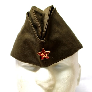 Könnte beinhalten: Olivgrüner Militärhut mit einem roten Stern-Emblem mit Hammer und Sichel. Der Hut ist dreieckig und scheint aus strapazierfähigem Stoff gefertigt zu sein. Das Emblem hat eine leuchtend rote Farbe.