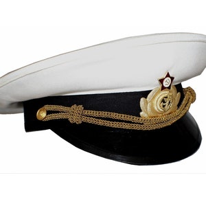 May include: A white naval officer's hat with a black band, gold braid, and a red star with a hammer and sickle emblem.