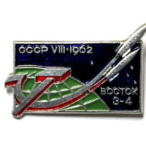 May include: Vintage USSR Vostok 3-4 space mission pin. The rectangular pin features a blue background with the text "CCCP VIII-1962" and "Vostok 3-4". The pin also includes a rocket, a hammer and sickle, and a green and red design.