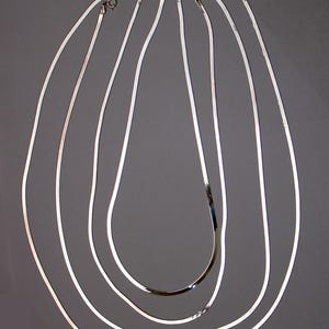 May include: Five silver snake chains of varying lengths, displayed on a gray background.