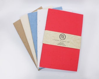 May include: A stack of five A5 notebooks with different colored covers. The covers are red, white, light blue, beige, and brown. The notebooks are made of plantable paper and have a label that says "Plantex Notebook A5" and "Handmade Notebooks".