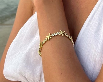 May include: A gold necklace and bracelet with a starburst design. The necklace is 38cm long. The model is wearing a white tank top and is standing on a beach.