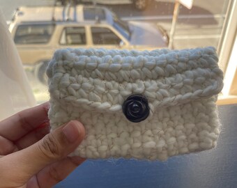 A milky white  Small hand-crocheted coin purse with dark  brown  flower button.