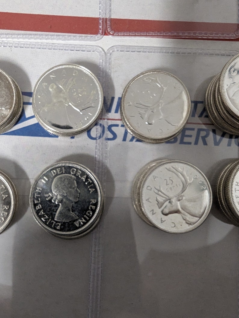 May include: A collection of silver Canadian coins featuring a variety of designs, including a portrait of Queen Elizabeth II, a caribou, and a loon.